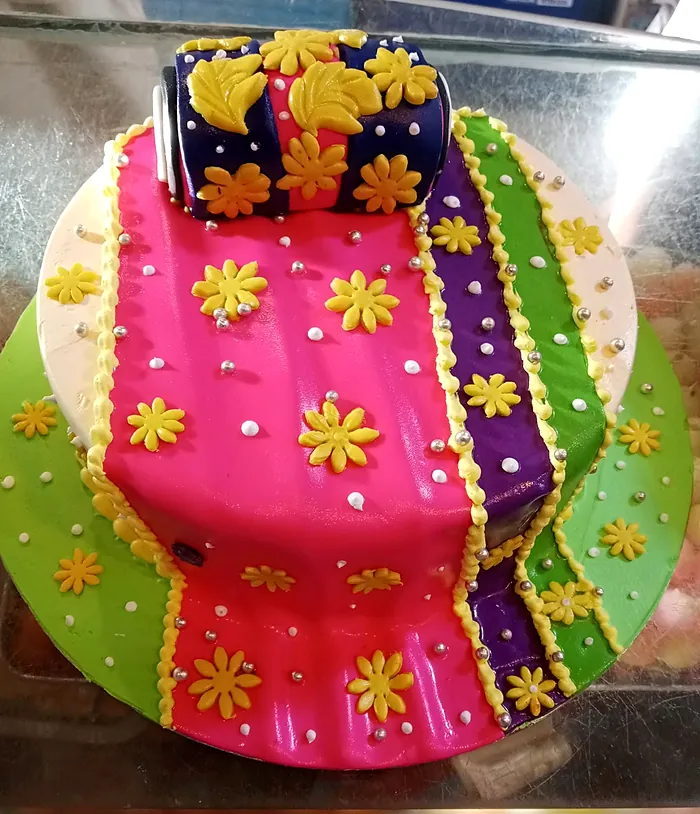 A dholki cake from Freshco: bright pink and green fondant dupatta with gold flowers and a small dhol on top