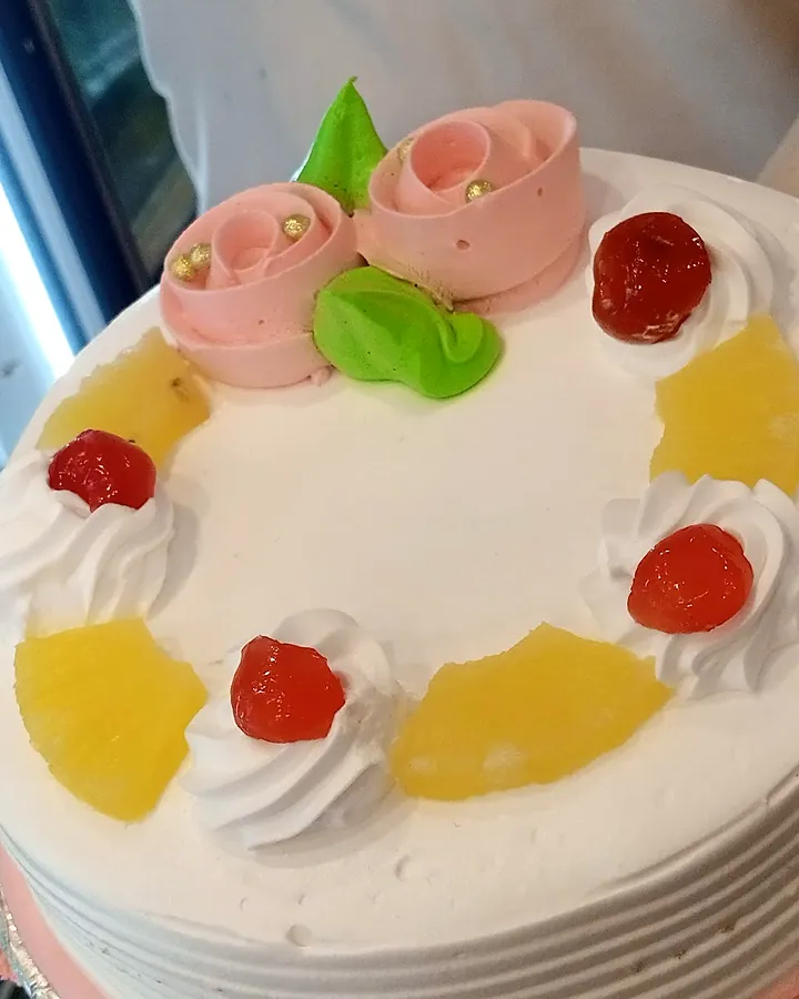 Fresh cream cake topped with fruit and cream roses
